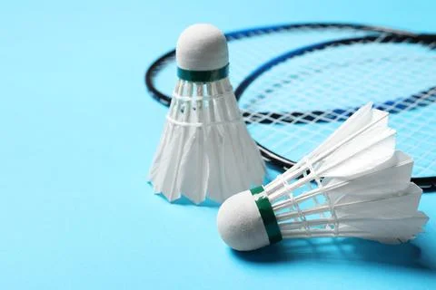 Feather badminton shuttlecocks and rackets on light blue background, closeu.. Stock Photos