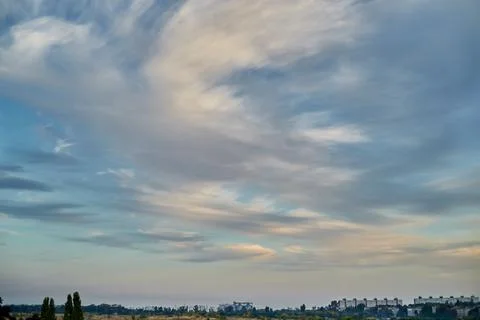 Feather clouds in the evening light on the blue sky over the fields and house Foto stock