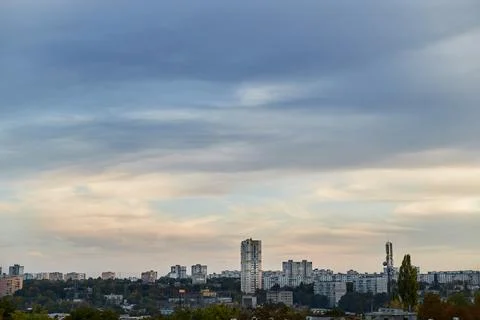 Feather clouds in the evening light on the blue sky over the city. Stock Photos