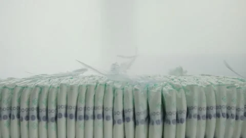 Feathers fall on a stack of baby diapers on a white background. The concept of Stock-Footage 253470426