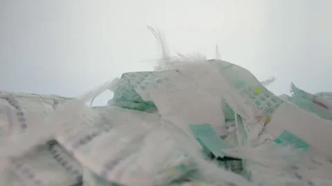 Feathers fall on a stack of baby diapers on a white background. The concept of Stock Footage 254060898