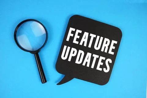 Feature Updates text with magnifying glass on blue background Stock Photos