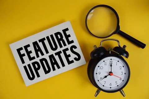 Feature Updates text written on paper with magnifying glass and alarm clock.. Stock Photos
