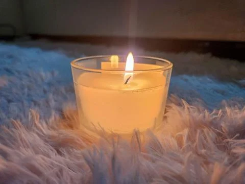 Featured object scented candle under a furry rug creating a cozy atmosphere Stock Photos