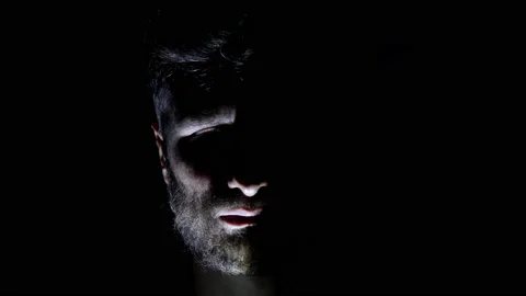 Features of a male, bearded face, backlit in the dark. Close-up of a man Stock Footage 159649799