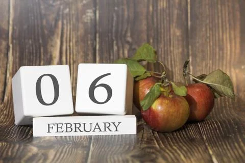 February 6. Day 06 of month. Calendar cube on wooden background with red appl Stock Photos