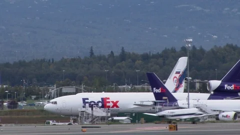 Fed Ex planes maneuver at Anchorage Airport as small plane lands. Stock Footage 79163232