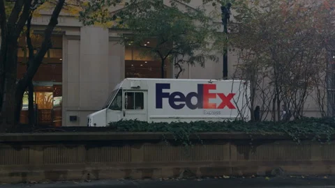 FedEx driver delivers package to local on a van in downtown. Front view. Chicago Stock Footage 294145836