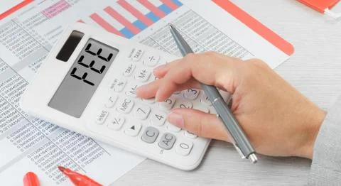Fee text on a calculator with financial data paperwork Stock Photos
