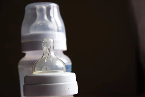 Feeding bottles with scale on dark background in kid's room Stock Photos