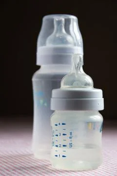 Feeding bottles with scale on dark background in kid's room Stock Photos