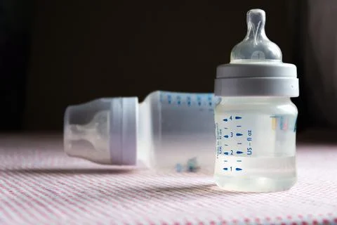 Feeding bottles with scale on dark background in kid's room Stock Photos