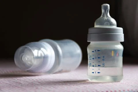 Feeding bottles with scale on dark background in kid's room Stock Photos