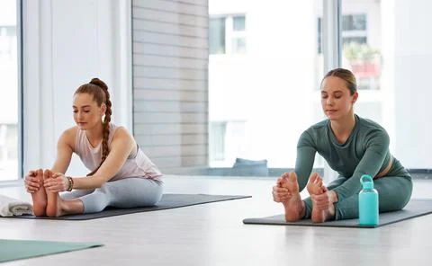 Feel the stretch in your hamstrings. Full length shot of two young women Stock Photos