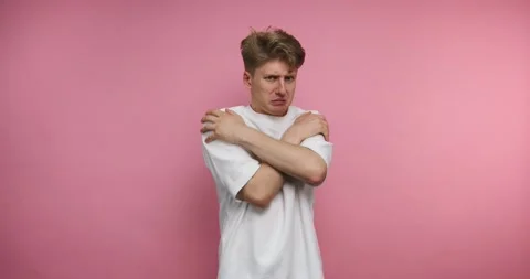 Feeling cold in a pink room while trying to stay warm with a simple t-shirt Stock Footage 317327995