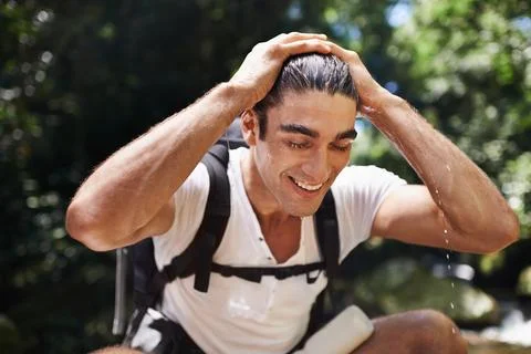 Feeling completely refreshed. A young man stopping for a break while out hiking Stock Photos