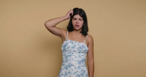 Feeling confused and unsure while posing in front of a solid background indoo 動画素材 326792664