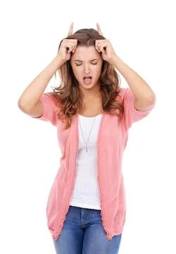 Feeling devilish. A young woman posing playfully with her fingers in horns above Stock Photos
