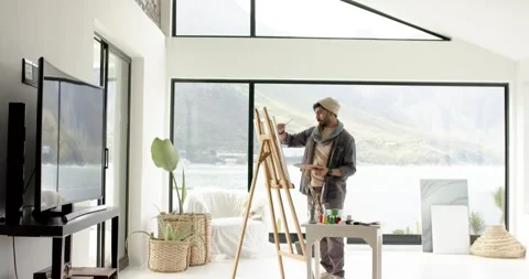 Feeling inspired Indian man in home studio painting lake view canvas with Stock Footage 340964401