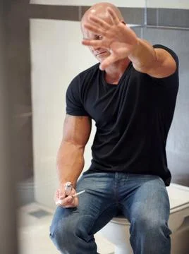 Feeling the shame. A bodybuilder sitting in the bathroom trying to hide from the Stock Photos