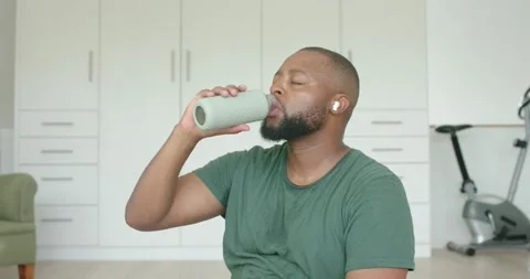Feeling thirsty, man lifting reusable water bottle, sipping while sitting in Stock Footage 338063977