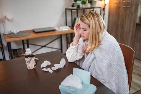Feeling unwell at home while wrapped in a cozy blanket and sipping tea Stock Photos