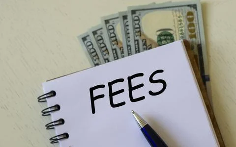 FEES word in a notebook with a pen against the background of dollar bills Stock Photos