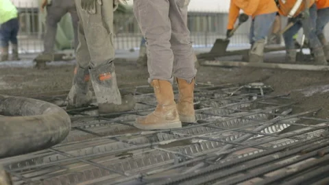 The feet of construction workers in rubber boots on  concrete pour. Video stock 144458456
