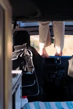 Feet dangling off the elevated bed of a camper van Stock Photos