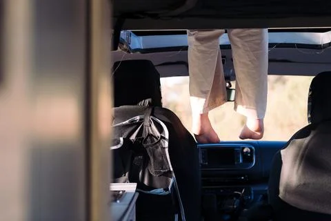 Feet dangling off the elevated bed of a camper van Stock Photos