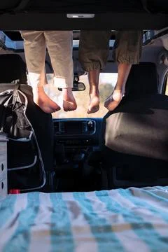 Feet dangling off the elevated bed of a camper van Stock Photos