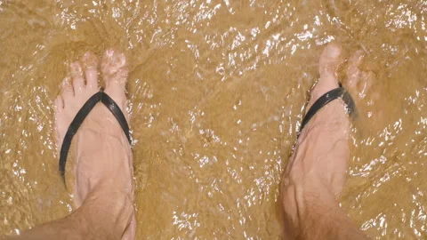 Feet in Flip-Flops Sink Slightly into Wet Sand as Gentle Waves Flow Over, Stock-Footage 279874117