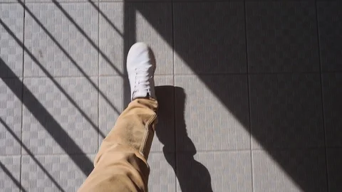 Feet of a man in white sneakers walking down the street. Pov video from the Stock Footage