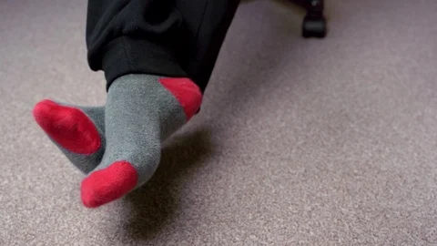 Feet in red-grey socks on a light brown carpet. A male in the chair Stock-Footage 124550505