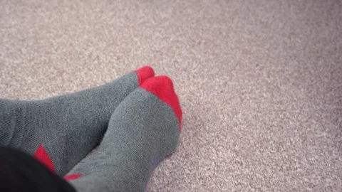 Feet in red-grey socks on a light brown carpet rub against each other Stock-Footage 124555440