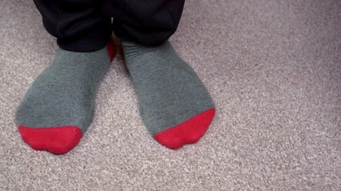 Feet in red-grey socks on a light brown carpet rub against each other Stock-Footage 124555659