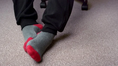Feet in red-grey socks on a light brown carpet. A male in the chair Stock-Footage 124556680