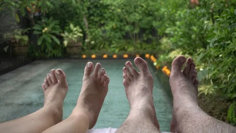 Feet of a resting young couple on the background of the pool in the rain. Stock Footage 104348377