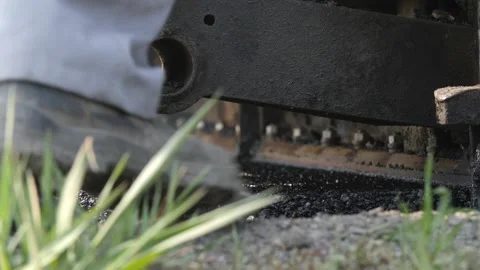 Feet of road construction worker in the front, paver lays asphalt in background Video stock 158040939