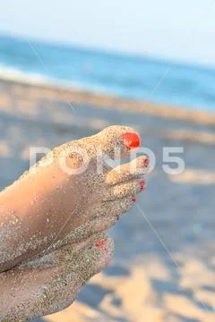 Feet on sand on a sunny beach Stock Photos