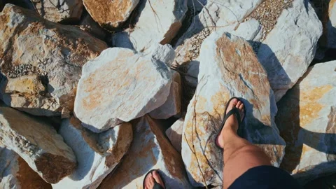 Feet in sandals tread over sun-dappled rocks Stock Footage 333514723