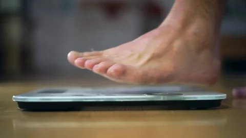 Feet stepping onto a scale Видео 89961504