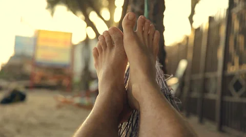 Feet swinging in a hammock, POV. Relaxing on the beach at sunset. Видео