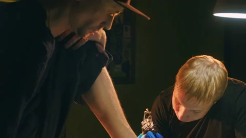 Feet tattoo pattern, face of focused tattooist artist with coil needle machine. Stock Footage 170009925