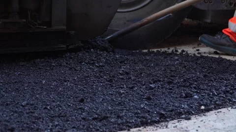 Feet of unknown construction workers spread asphalt on the ground Stock Footage 251890110