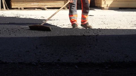 Feet of unknown construction workers spread asphalt on the ground Stock Footage 251890128
