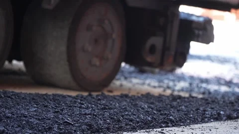 Feet of unknown construction workers spread asphalt on the ground Видео 251890191