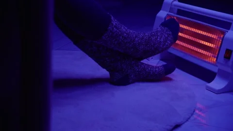 Feet warming by electric heater in cold room Stock Footage 292877160