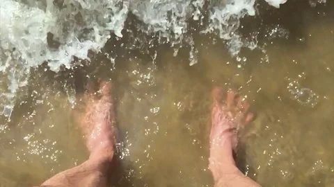 Feet waves of sea slow motion video man. male tourist is standing with his feet Stock Footage