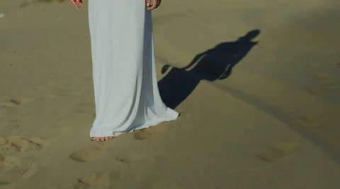 Feet of woman walking on beach dunes in white dress while sun drops shadow slow Video stock 59742066